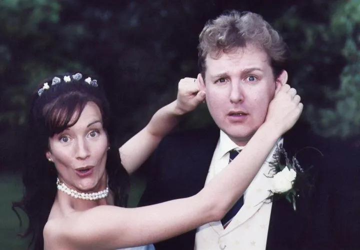 Miriam, mock-surprised, tugging both of Alex's ears as he pulls a startled face